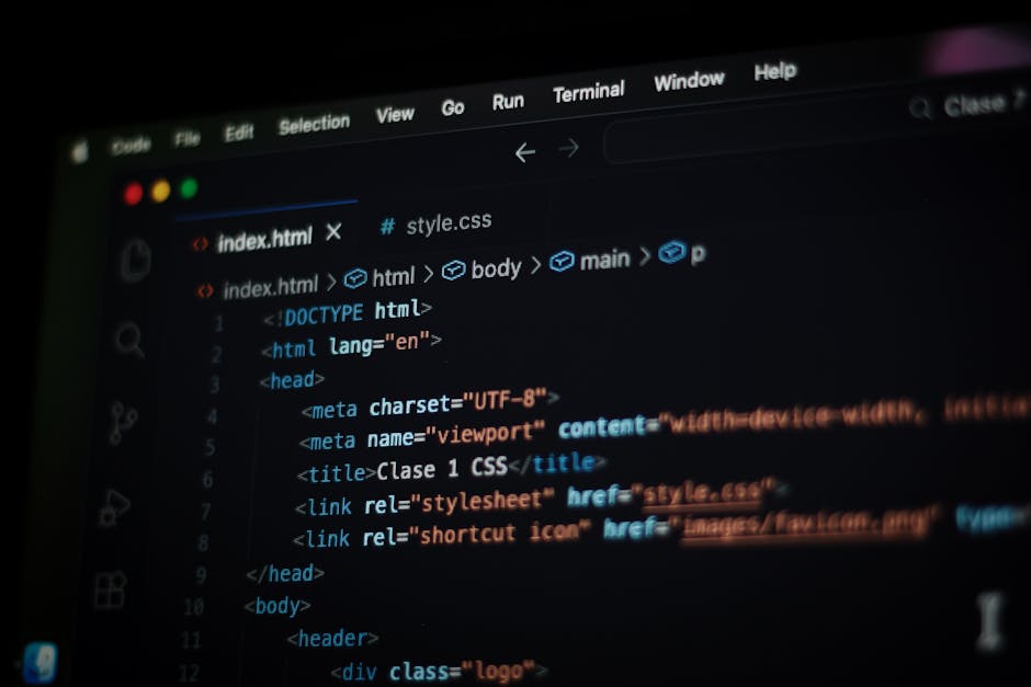 A close-up view of a person's hands using a laptop computer on a dark surface. The laptop's screen displays lines of code with syntax highlighting in green, blue, and white text on a black background.